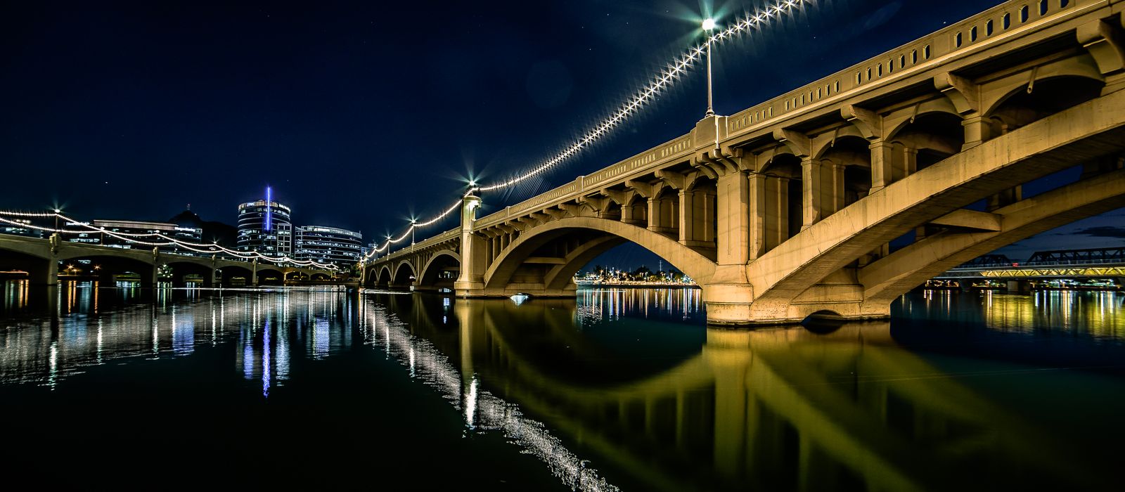 Stunning night view of the illuminated bridge at Tempe Town Lake, Arizona, reflecting in the water.