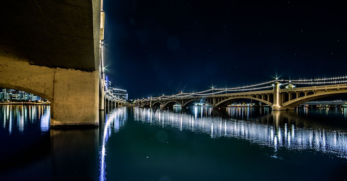 Stunning nighttime shot of Tempe Town Lake bridge with reflections, stars, and city lights.
