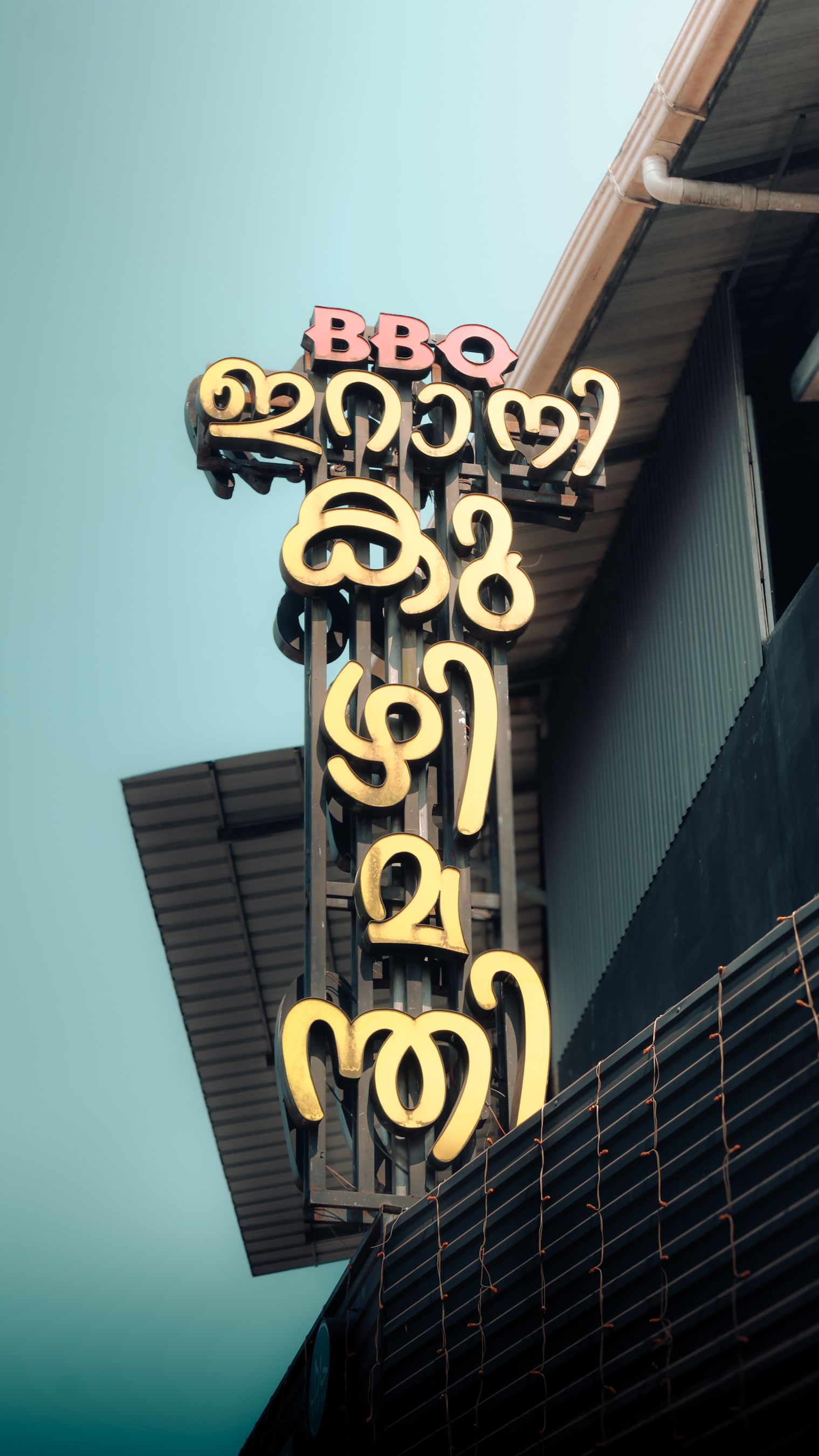 Close-up of BBQ restaurant sign in Malayalam on a building in India.