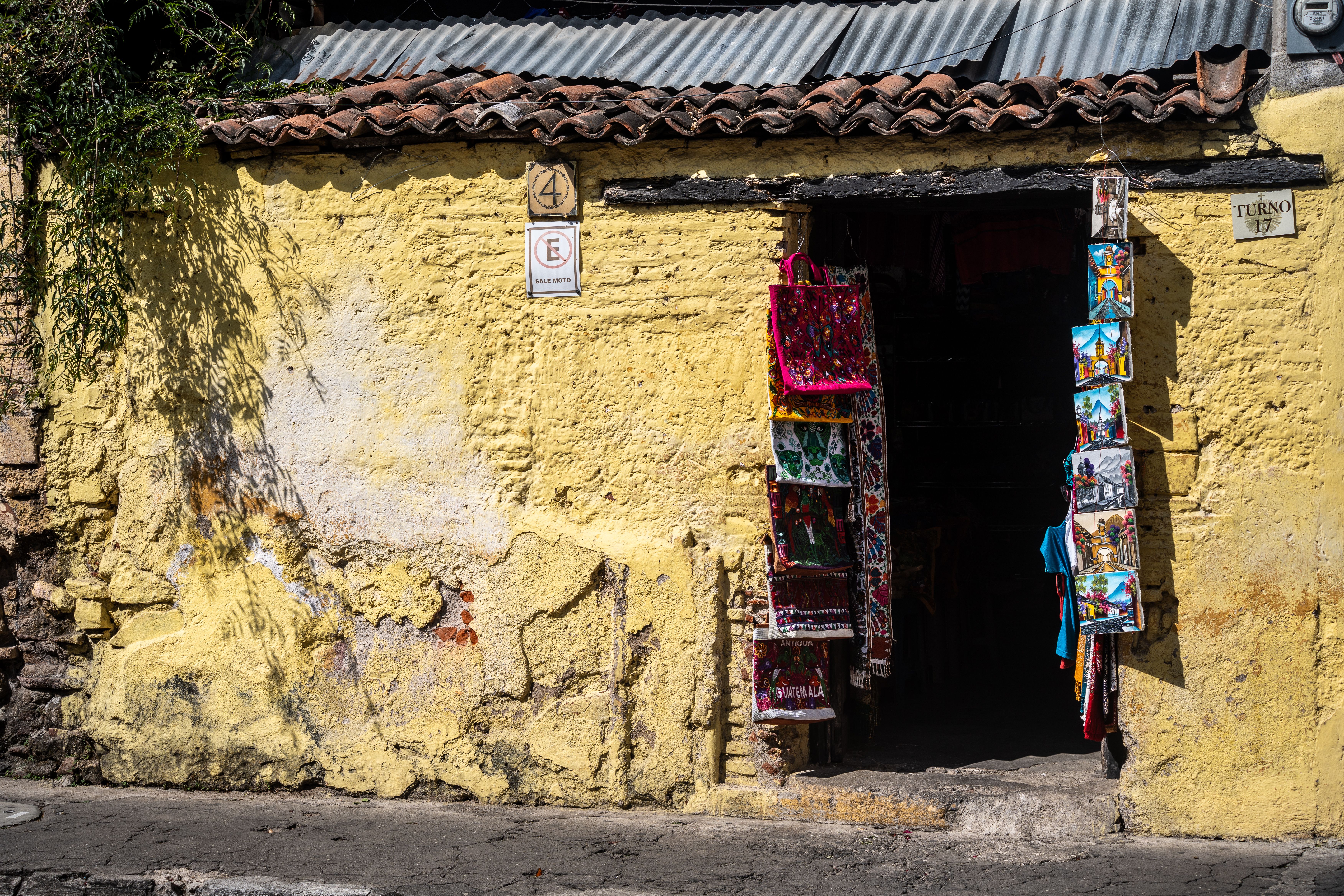 Rustic market stall with vibrant textiles on a sunny cobblestone street.