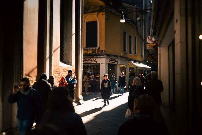 Pedestrians filling a narrow alleyway in warm light &mdash; photo by Gabriel Rojas Acevedo on Pexels