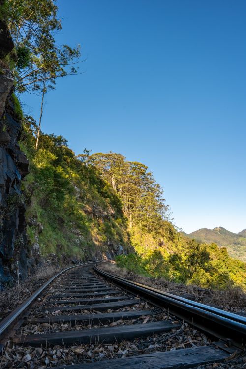 Free A scenic railway track meandering through lush green hills in Sri Lanka under a clear blue sky. Stock Photo
