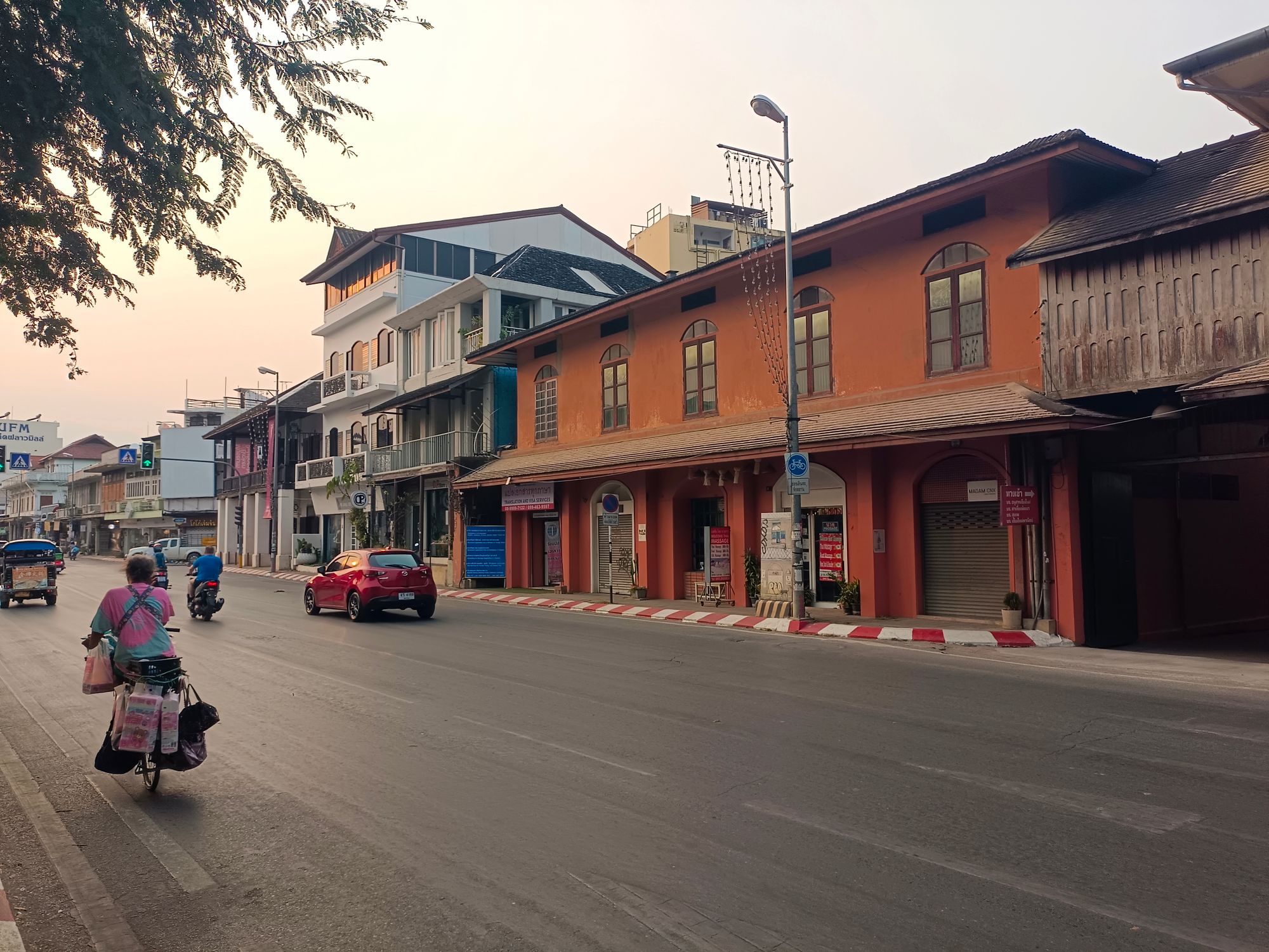 A lively street in Chiang Mai with people and vehicles under the soft evening light