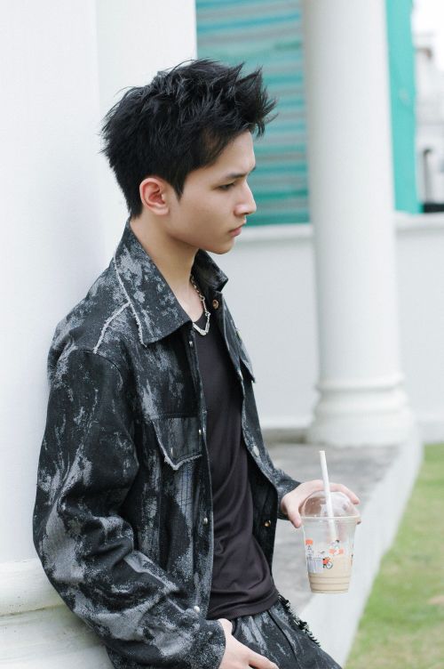 Free Stylish young adult holding iced coffee standing outdoors, exuding a casual vibe. Stock Photo