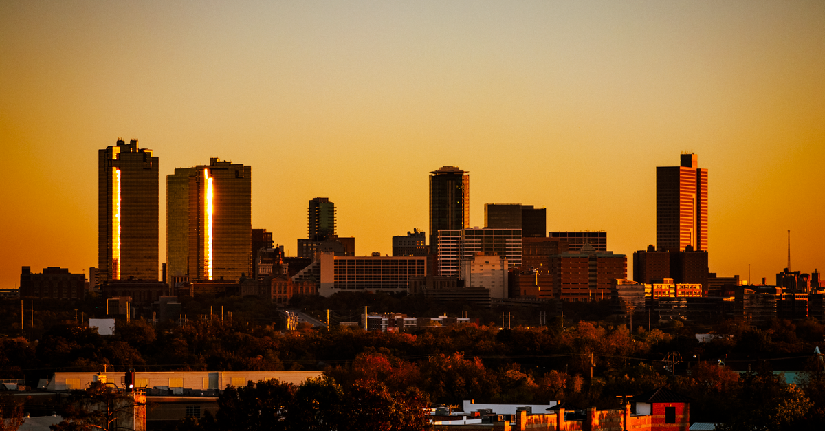 Dramatic sunset view of Fort Worth, Texas skyline. Warm tones highlight the city's architecture.