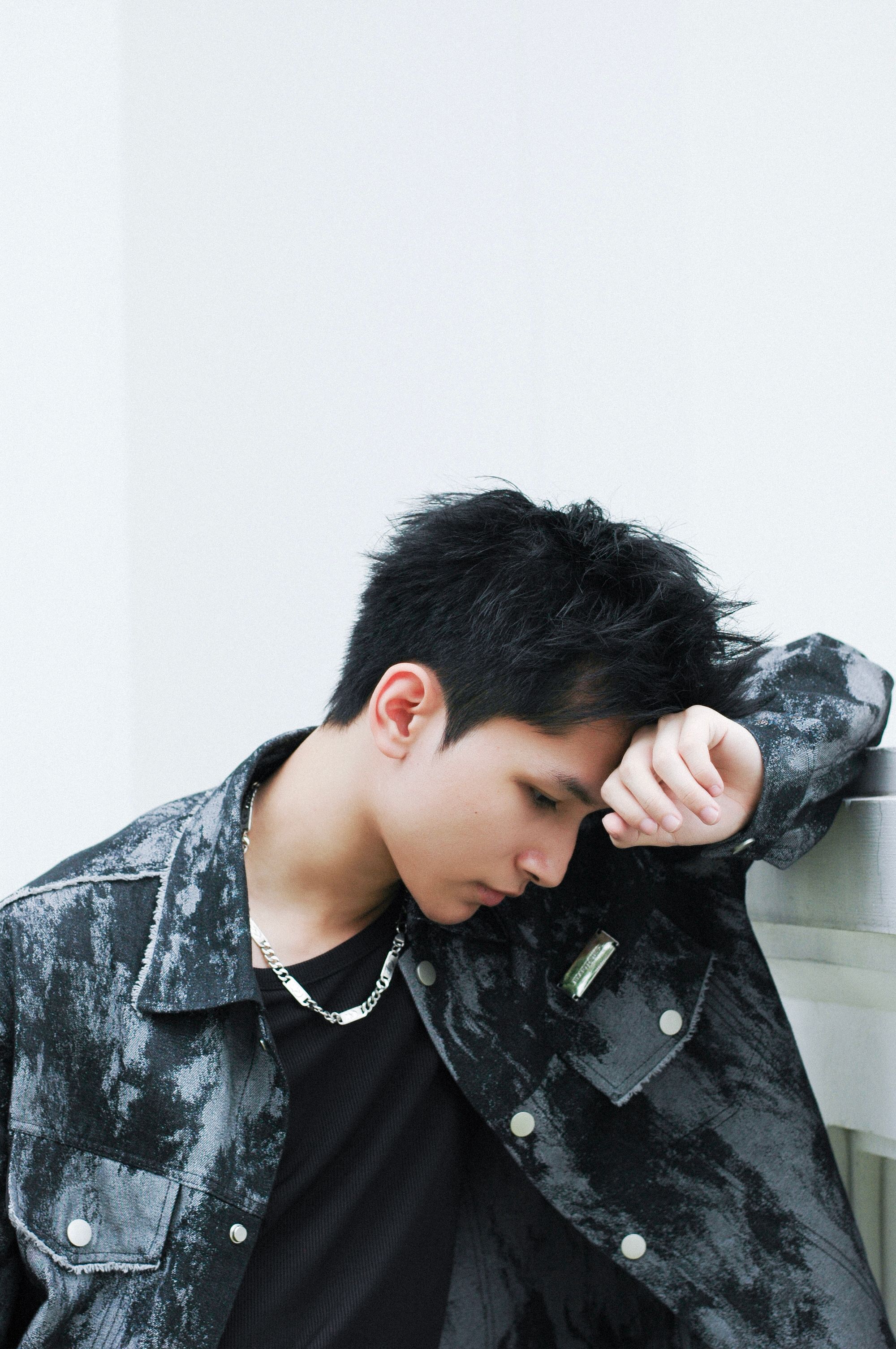 Portrait of a stylish young man in a pensive moment, indoors with minimalistic background.