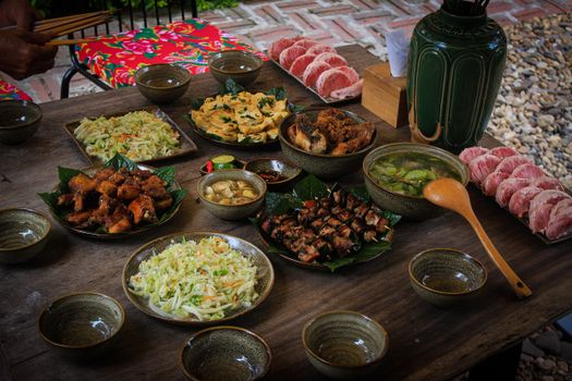 An appetizing spread of Vietnamese cuisine on an outdoor wooden table, perfect for food enthusiasts.