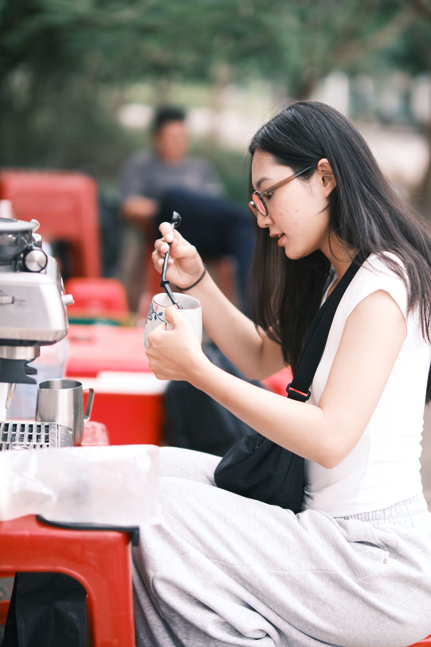 Người phụ nữ Việt thưởng thức cà phê tại quán cà phê ngoài trời