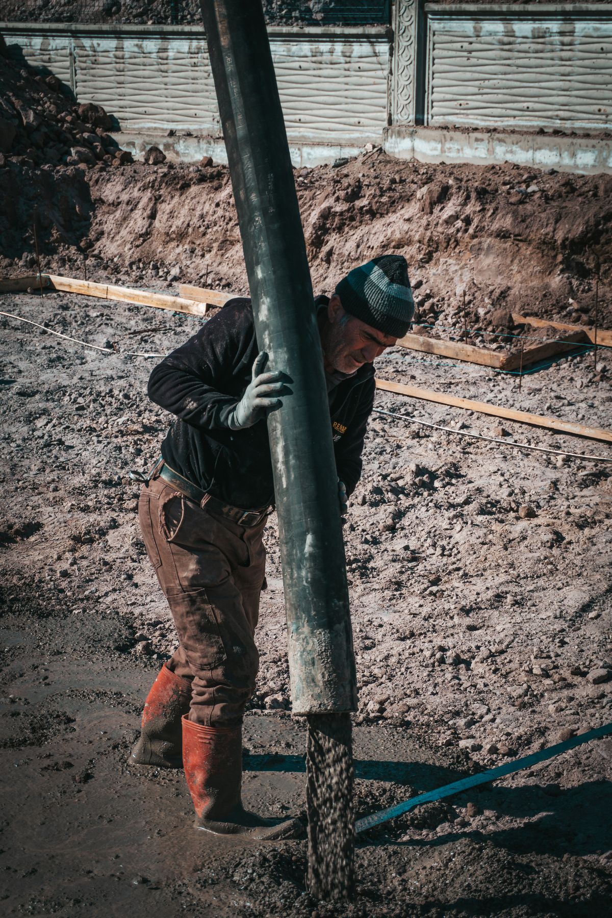 Bauarbeiter gießt frischen Beton für ein Fundament auf einer Baustelle