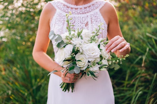 Woman in White Floral Sleeveless Dress Holding White Rose Bouquet