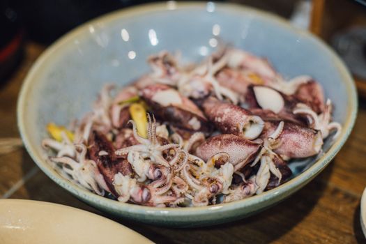 Close-up of fresh squid in a ceramic bowl, showcasing texture and color for culinary inspiration.