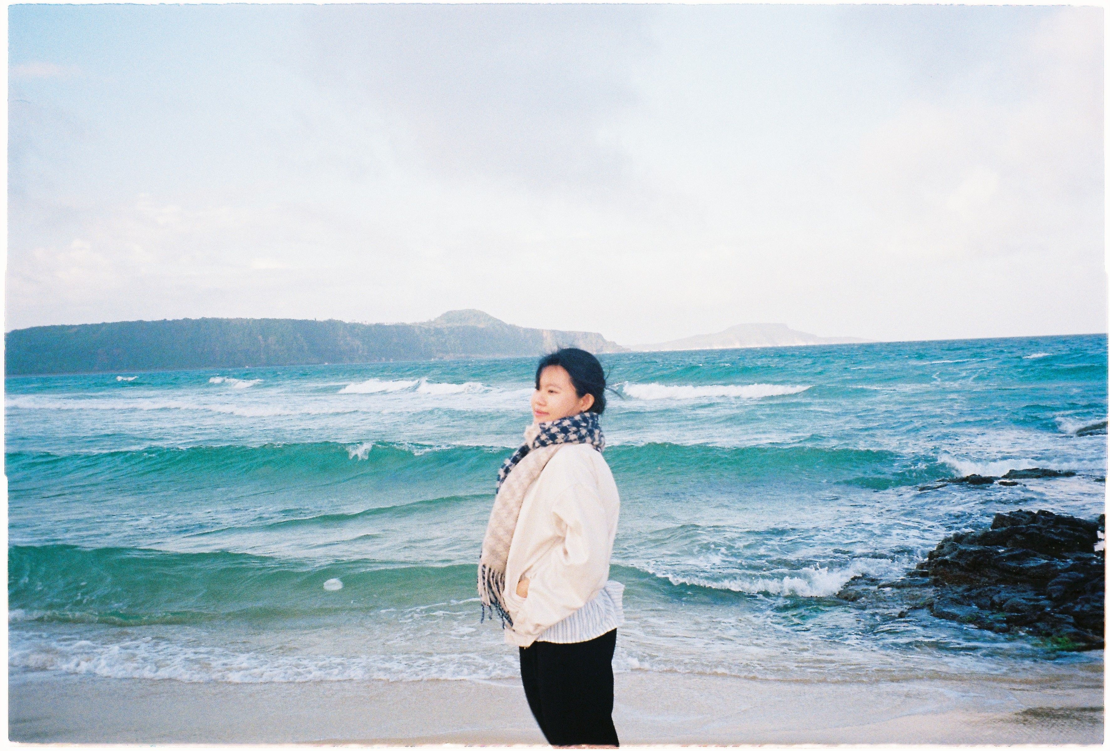 A young woman stands by the vibrant coastal beach in Tuy An Nam, Vietnam.