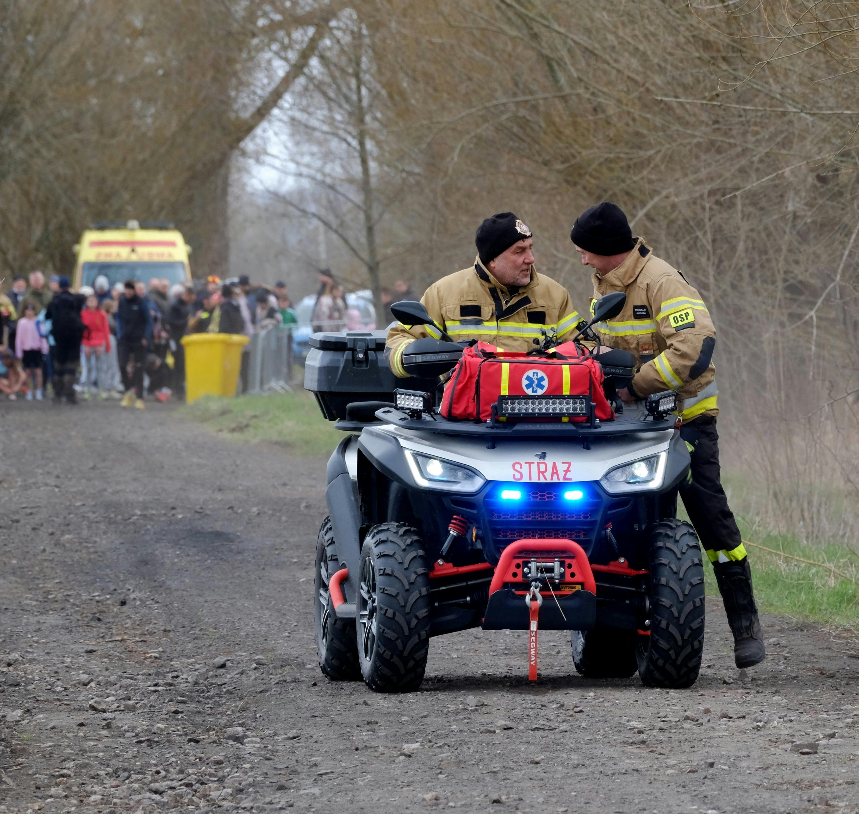 Firefighters on an ATV coordinating an emergency rescue operation on a rural path.