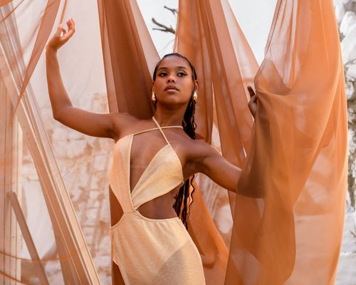 Free Stylish woman in elegant attire poses with flowing fabric outdoors in São Paulo. Stock Photo