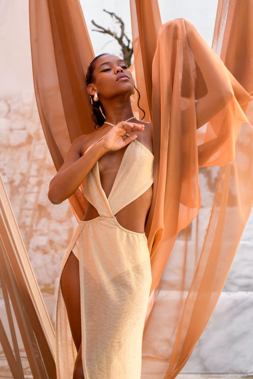 Free A woman in an elegant dress poses gracefully surrounded by flowing fabric outdoors. Stock Photo