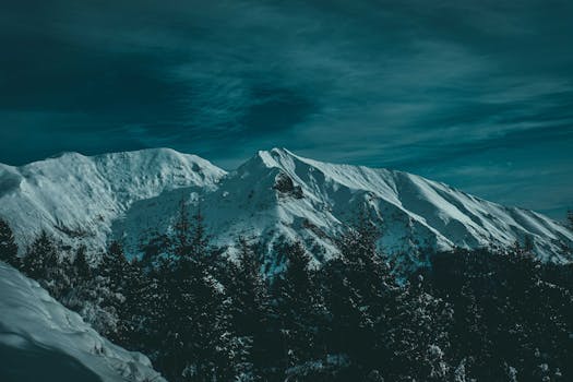 Serene snow-covered peaks with dark sky creating a dramatic winter landscape.