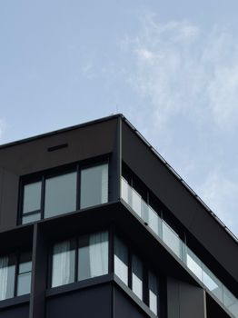 A stylish modern apartment building with large windows under a clear blue sky in Vienna, Austria.