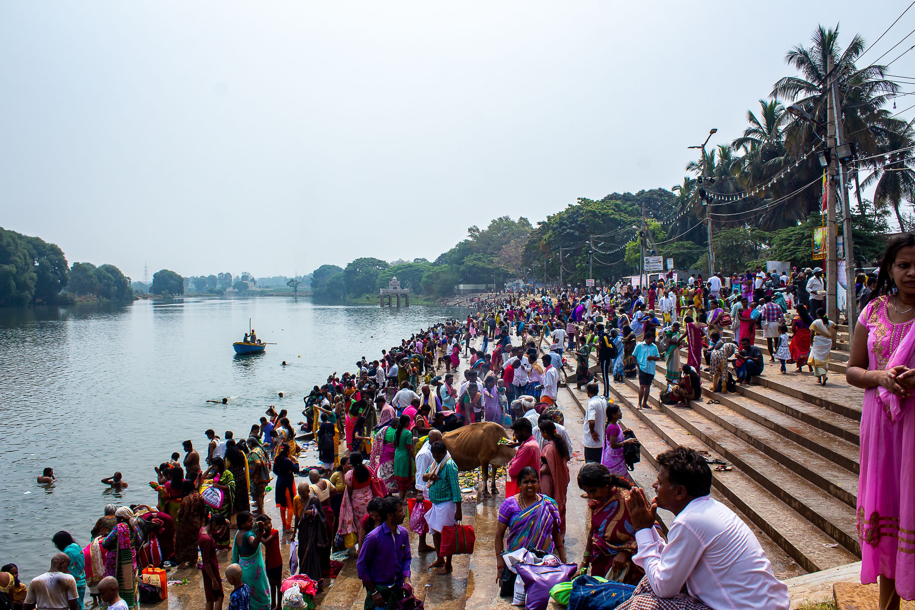 Colorful crowd gathered at a riverbank in South Asia, showcasing cultural diversity and traditional attire.