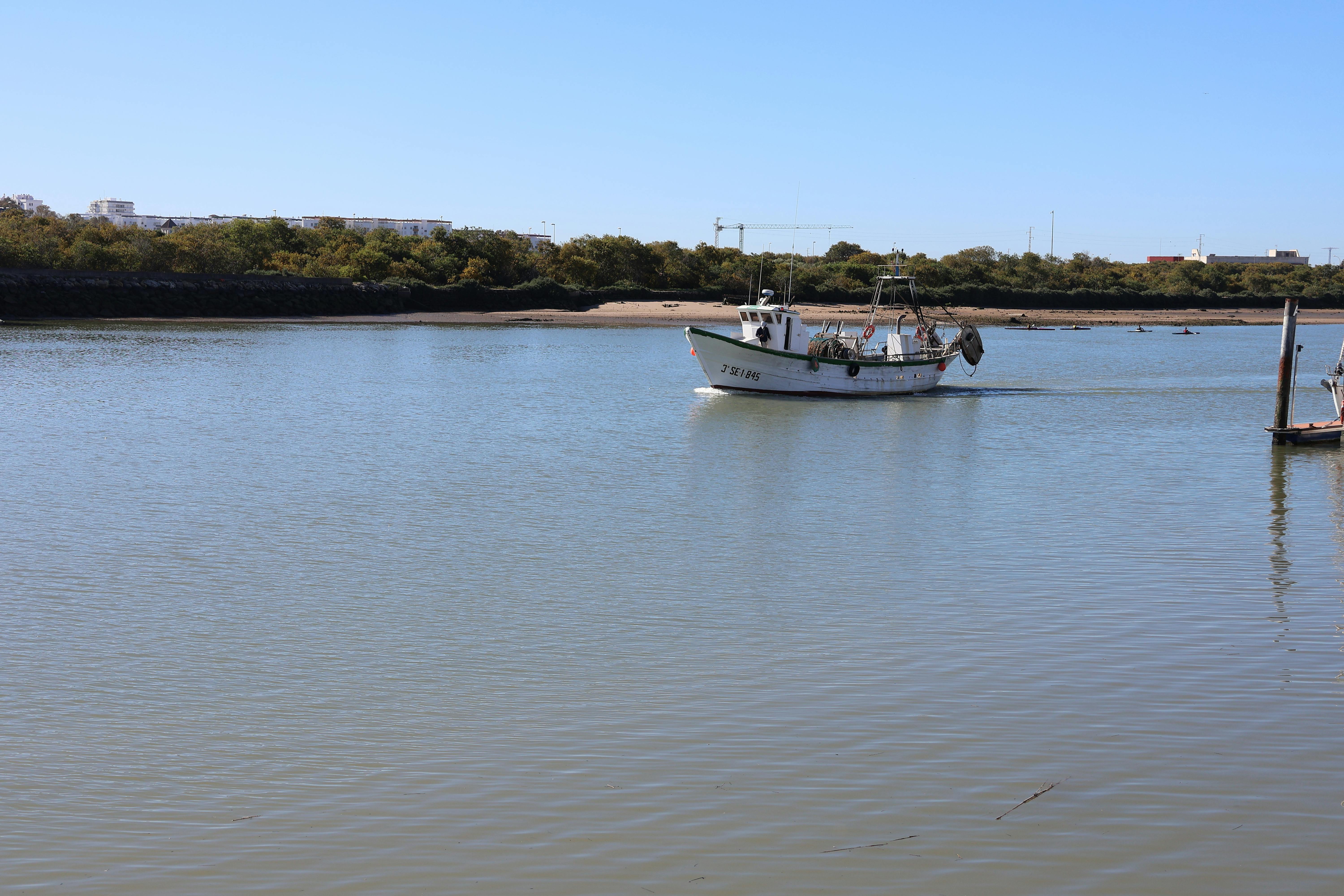 A serene view of a fishing boat on the Guadalete River in El Puerto de Santa María, Spain.