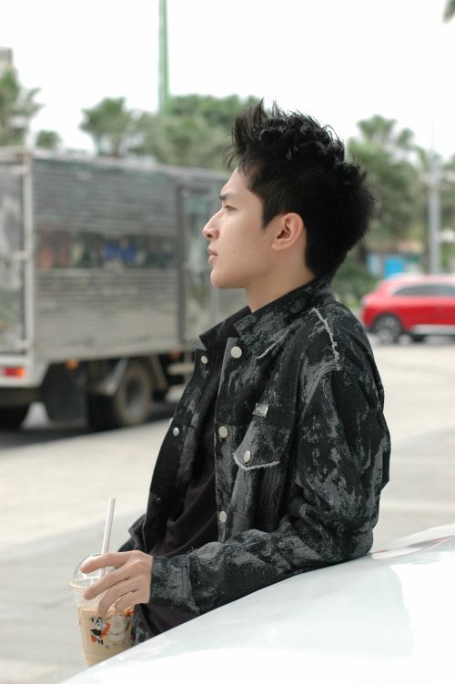 Free Profile of a young man with bubble tea, leaning on a vehicle in an urban setting. Stock Photo