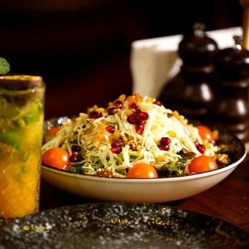 Free A vibrant salad featuring pomegranate seeds and cherry tomatoes accompanied by a refreshing mint drink. Stock Photo