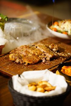 Delicious roast meat with sides on a wooden board. Perfect gourmet meal.