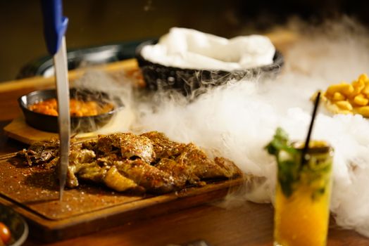 Deliciously grilled meat served with side dishes and a refreshing cocktail garnished with mint.