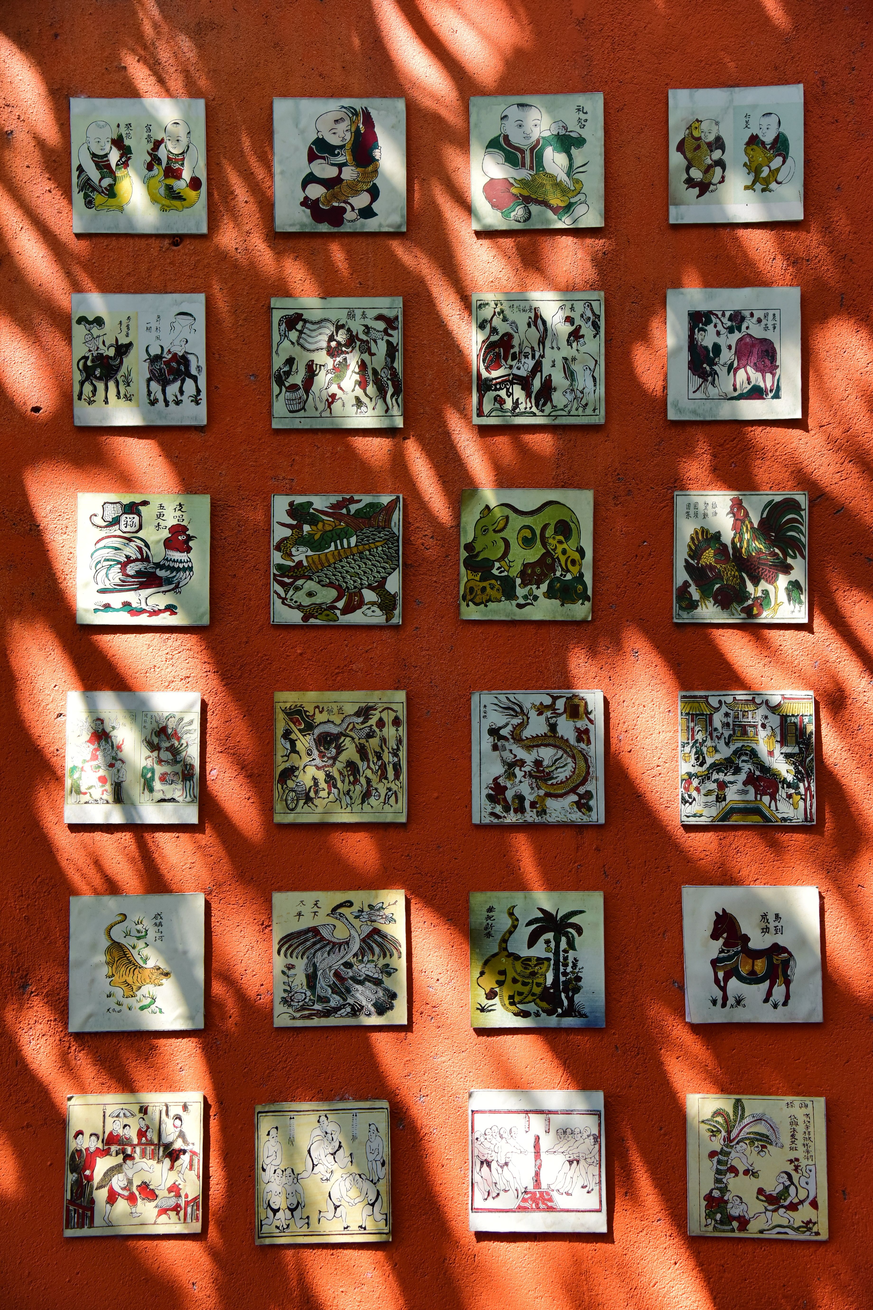Colorful tiles featuring Chinese zodiac animals adorn an orange wall, creating a vibrant, artistic display.