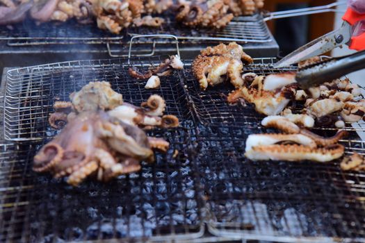 Close-up of octopus grilling outdoors, showcasing savory seafood preparation.