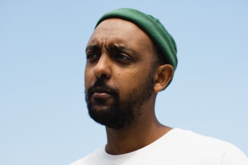 Free Portrait of a pensive man in a green beanie against a clear blue sky. Stock Photo