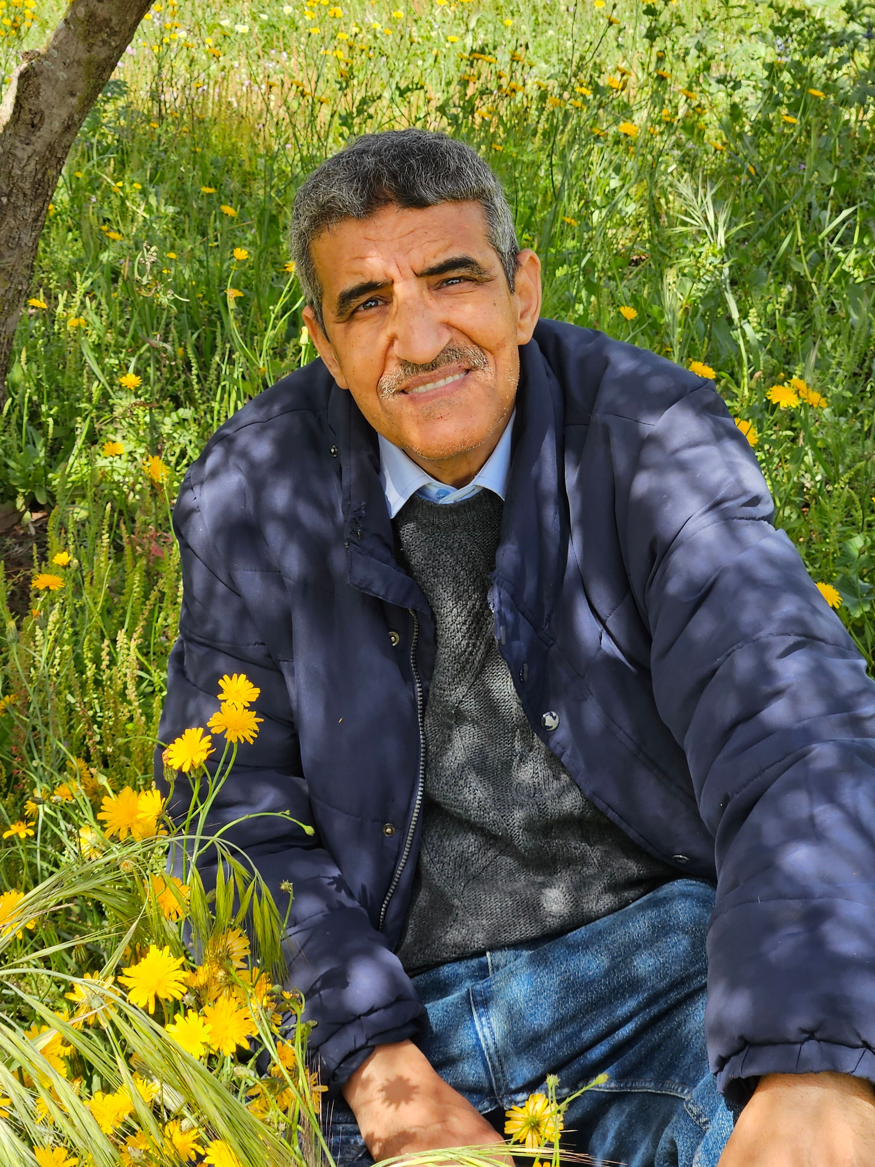 A senior adult man enjoying a peaceful moment in a lush spring meadow with yellow flowers.