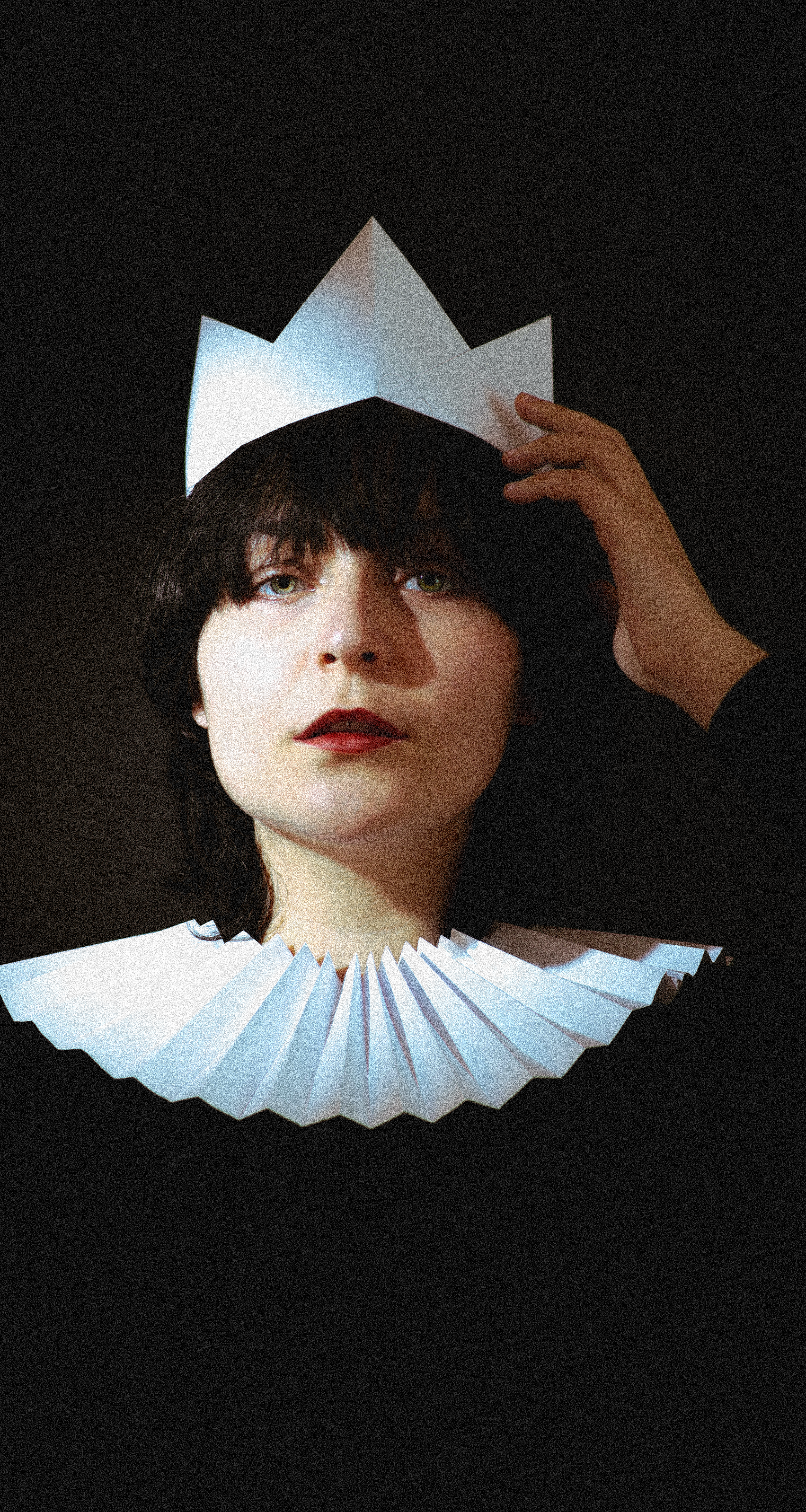 A creative portrait of a person wearing a paper crown and collar in vintage style.