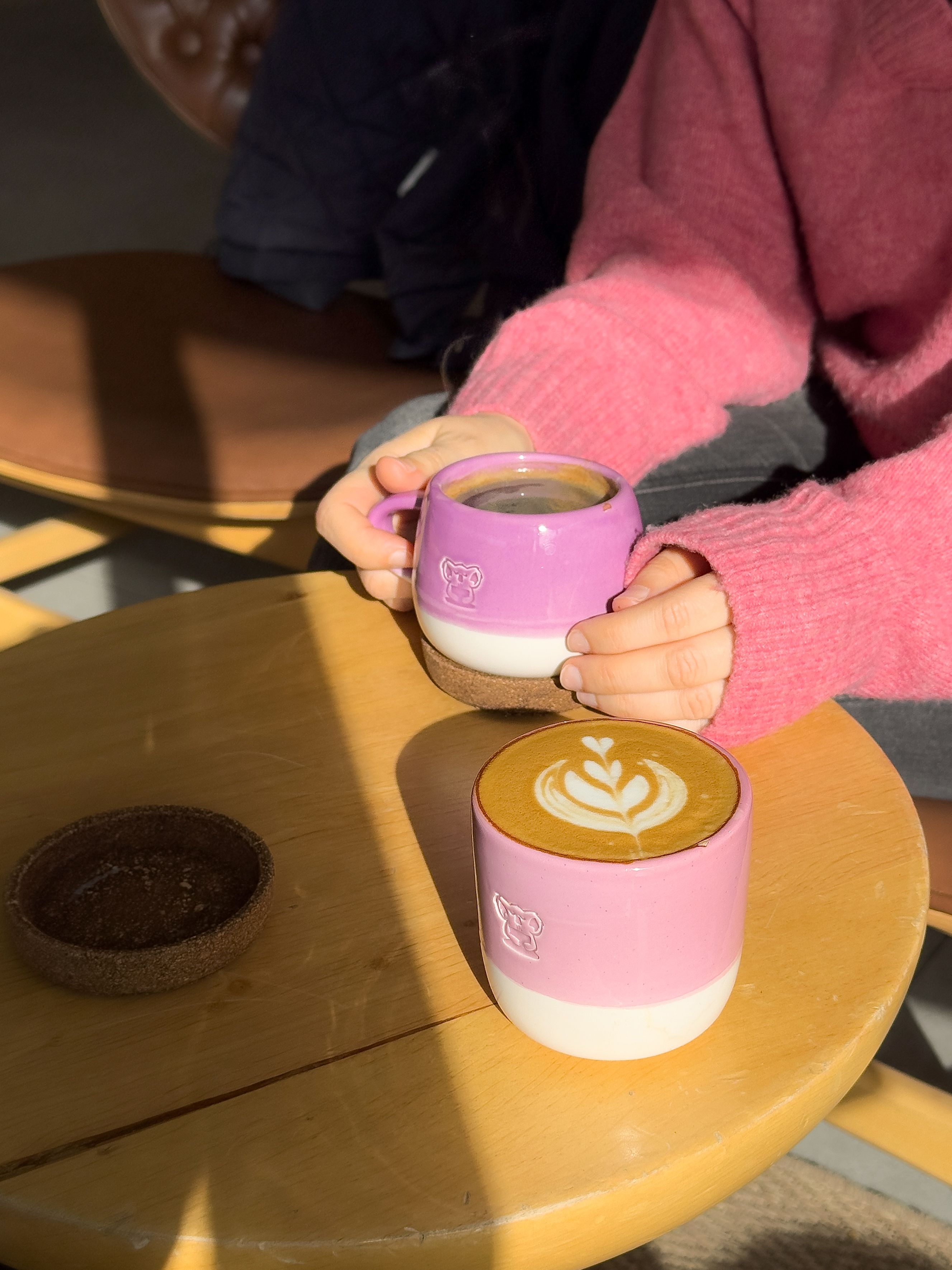 A close-up of a person enjoying coffee with latte art in a sunlit café in Istanbul.