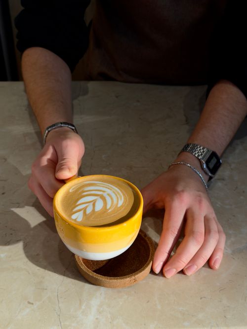 Free Close-up of a barista serving a cappuccino with latte art in a cozy Istanbul café. Stock Photo