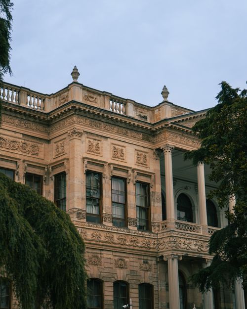 Free Vintage European building facade with ornate details and lush greenery. Stock Photo
