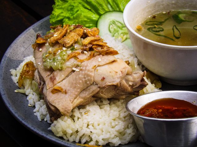 A classic dish of Hainanese chicken rice served with flavorful soup and spicy sauce.