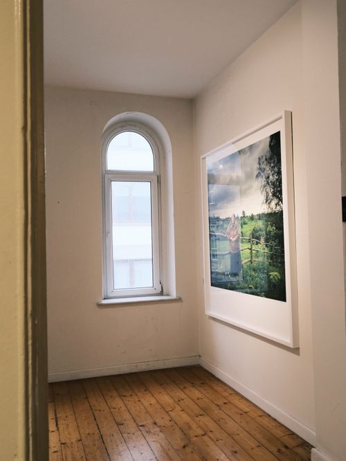 Free A bright hallway with an arched window and framed artwork on a wooden floor. Stock Photo