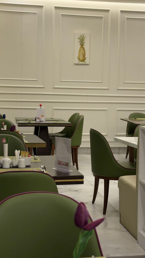 Free Stylish indoor cafe setting with green chairs, white walls, and a pineapple artwork. Stock Photo
