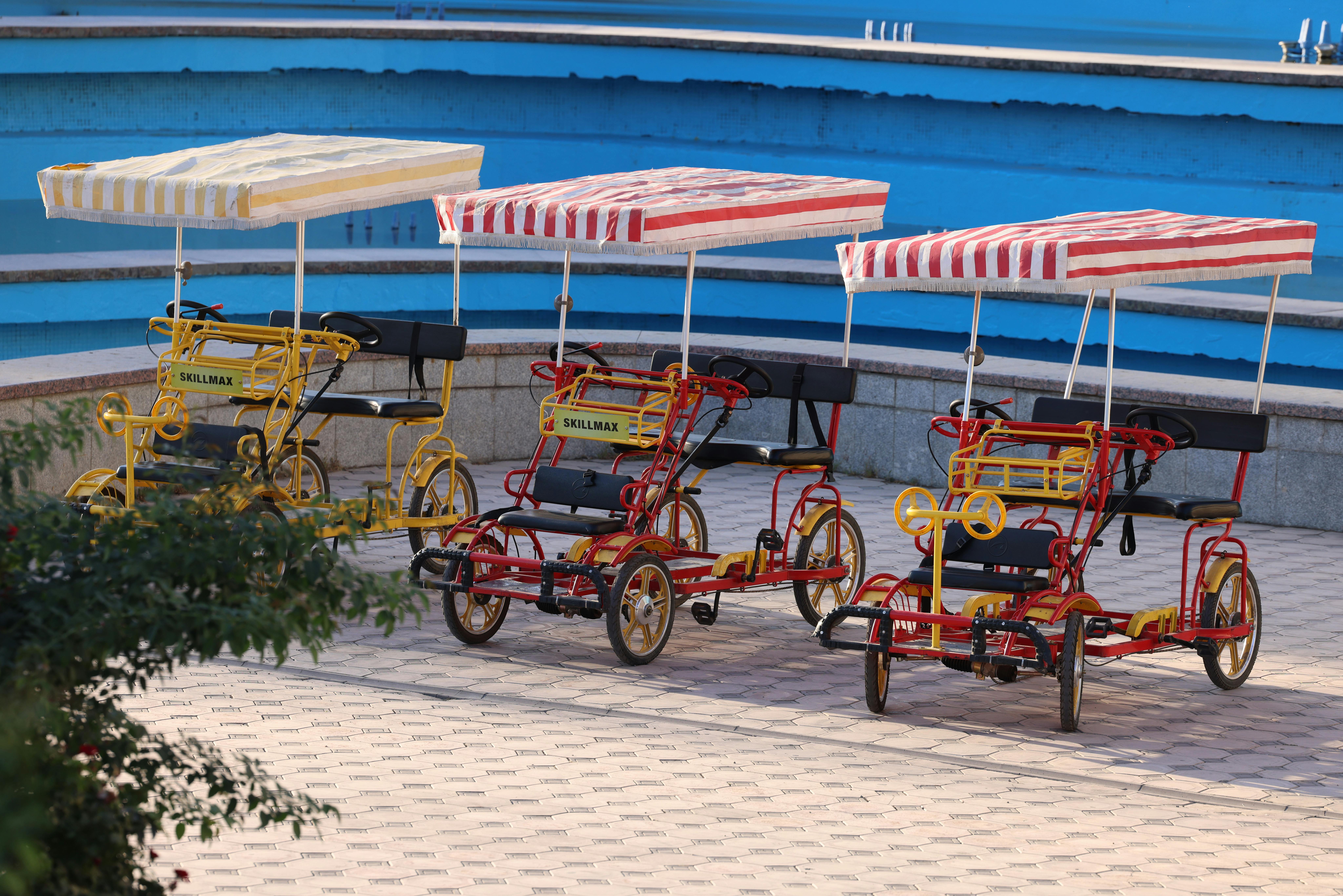 Vibrant quadricycles with striped canopies parked outdoors in Uzbekistan, perfect for leisurely rides.