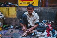 An artisan cobbler in Varanasi skillfully repairs shoes at Munshi Ghat, showcasing traditional craftsmanship.