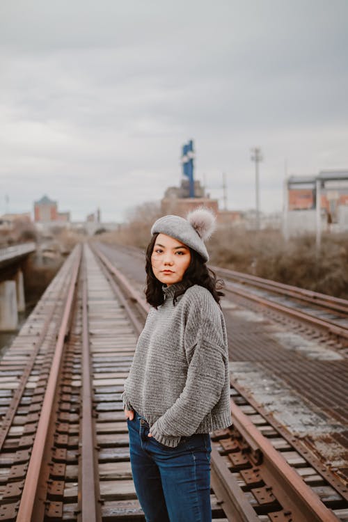 Mujer En Suéter De Punto Gris Y Pantalones Vaqueros Azules De Pie En El Carril Del Tren