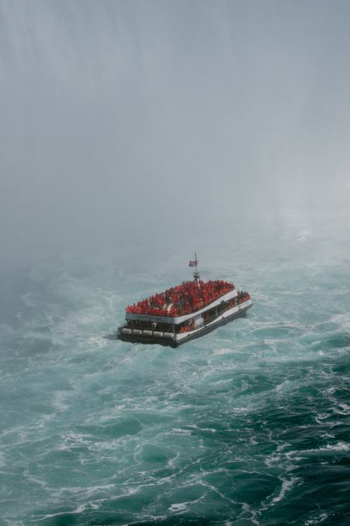 Free Tourists in red raincoats enjoy a boat ride near Niagara Falls amid mist and swift waters. Stock Photo