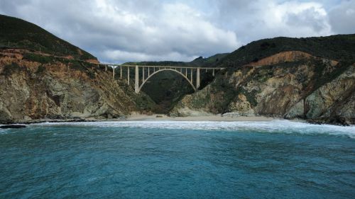 Free Scenic view of Bixby Creek Bridge along California's rugged Big Sur coastline with ocean waves and cliffs. Stock Photo