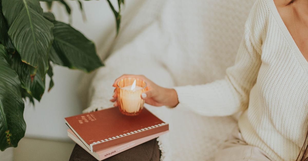 A person in comfortable loungewear walking on a walking pad at home, with soft lighting and a candle nearby
