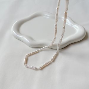 Freshwater pearl necklace on a pale surface, photo by TinyPearl xoxo on Pexels