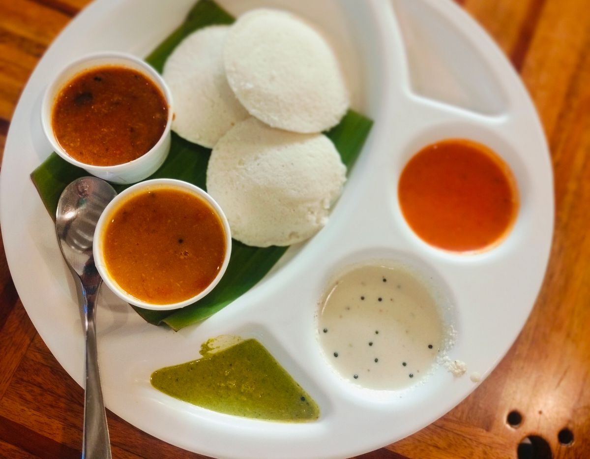 Idli served with an assortment of chutneys and sambar