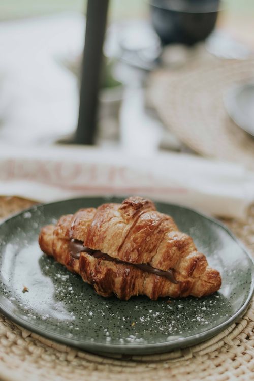 Free Close-up of a fresh croissant on a rustic green plate, perfect for breakfast. Stock Photo