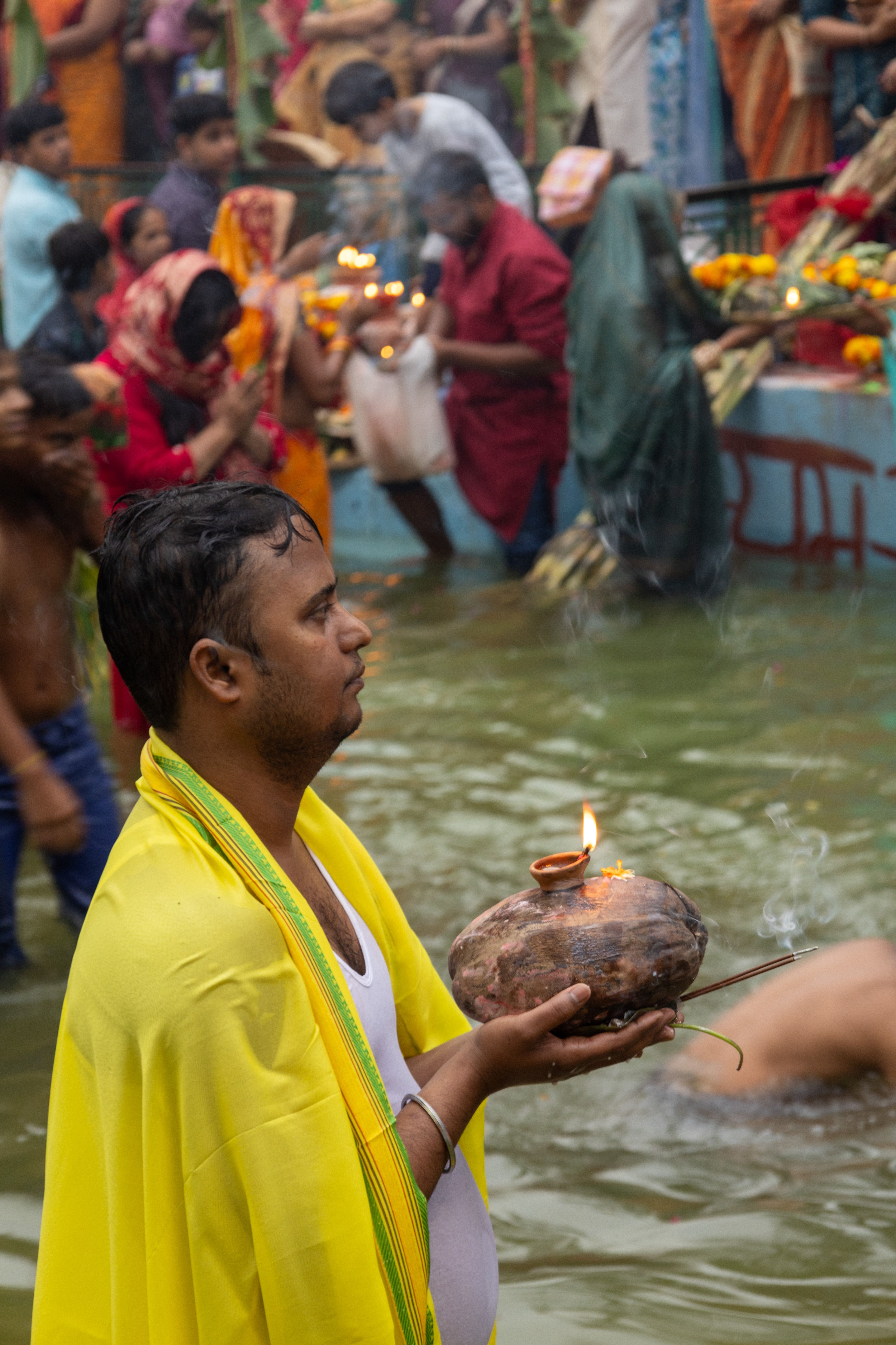 A devotee engages in Chhath Puja, holding a diya at a river ceremony in India.
