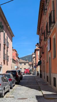 Sunlit cobblestone street lined with colorful buildings in a quaint European village.