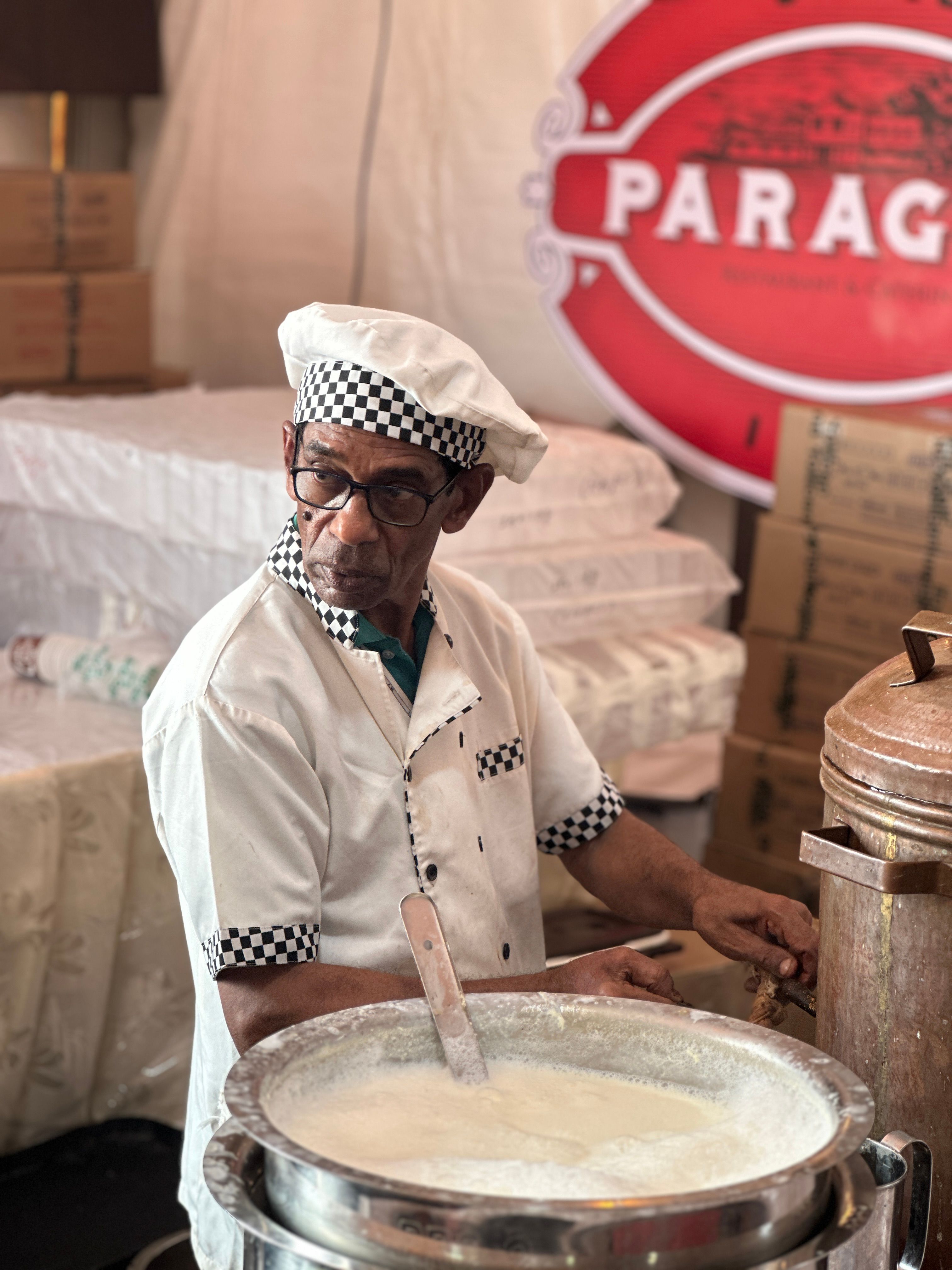 Senior cook in traditional attire preparing an Indian dish